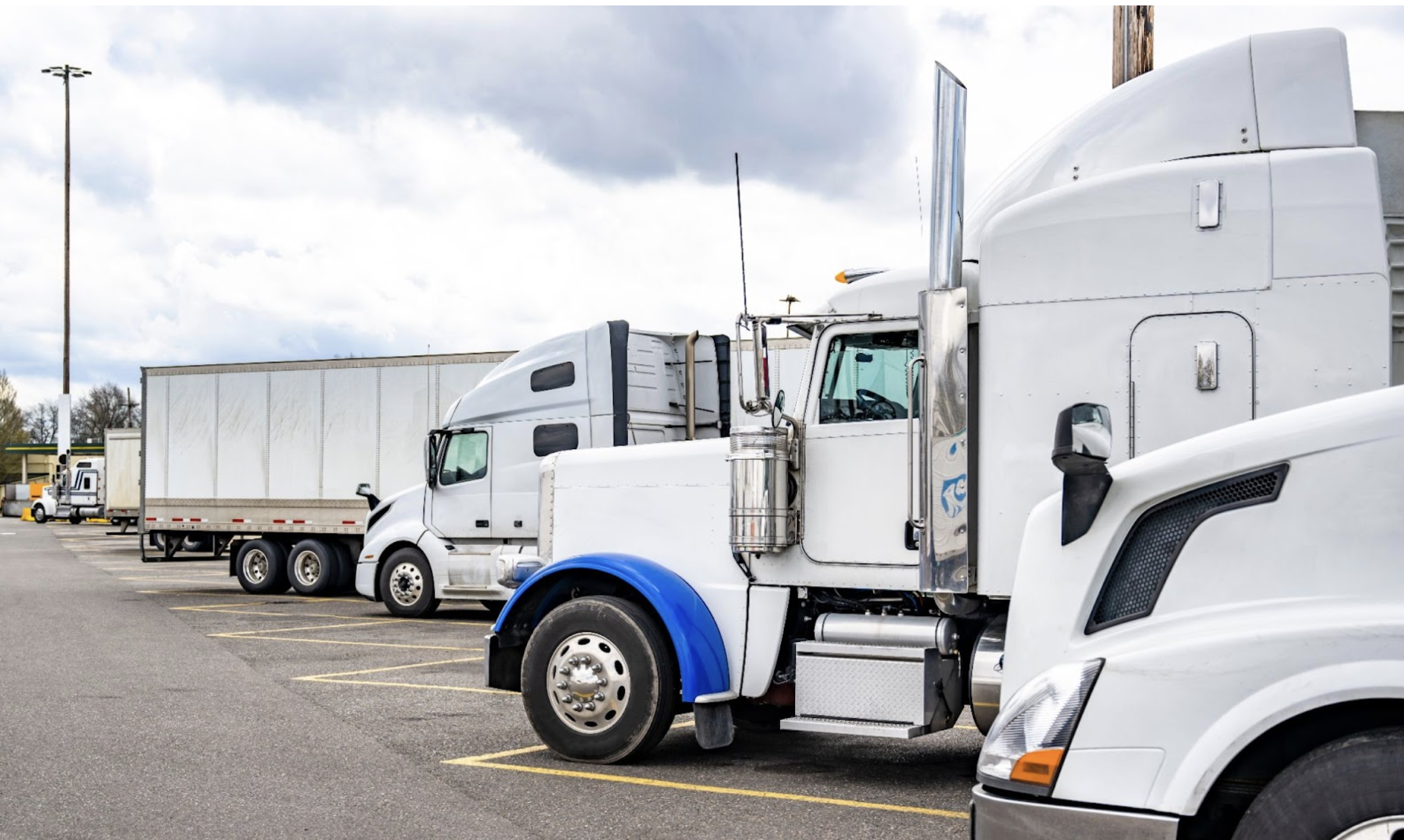 semi trucks with semi-trailers standing in row on truck stop parking lot